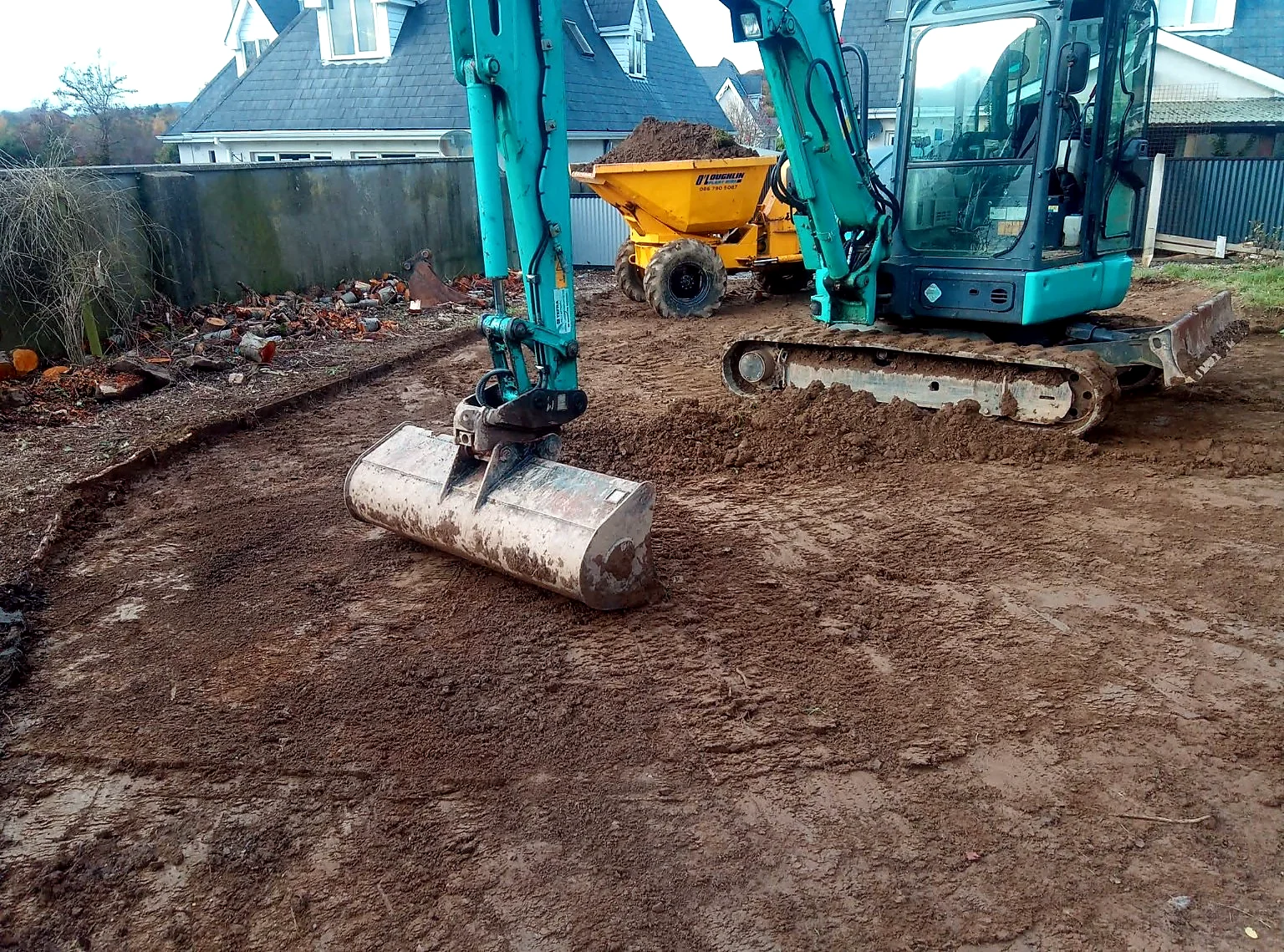 Excavator and site dumper working beside houses
